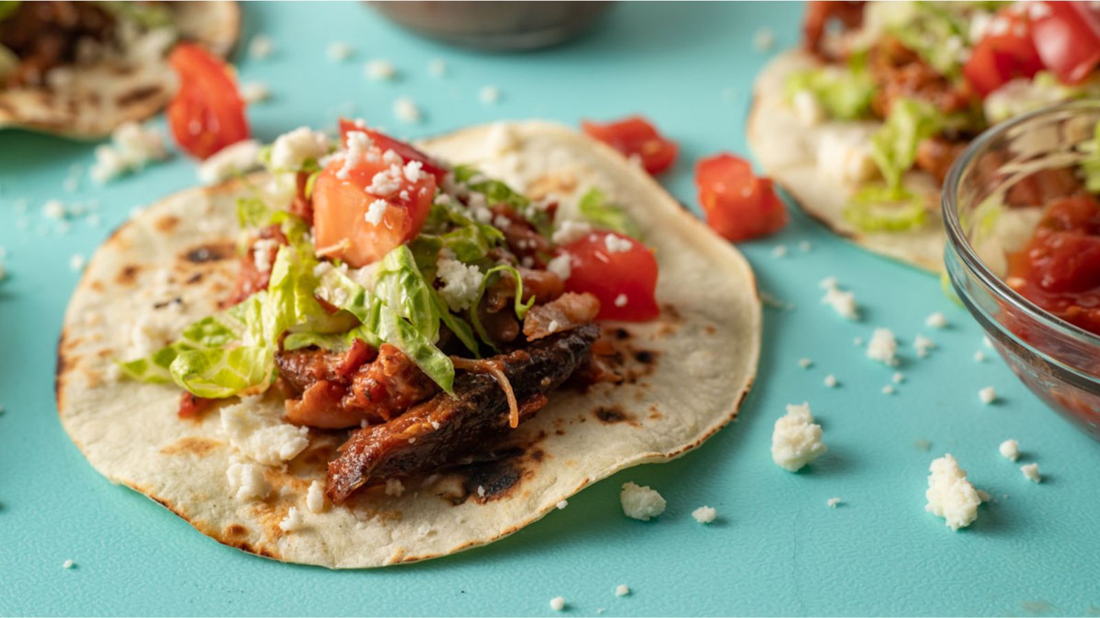 Meaty rabbit taco on blue green board.