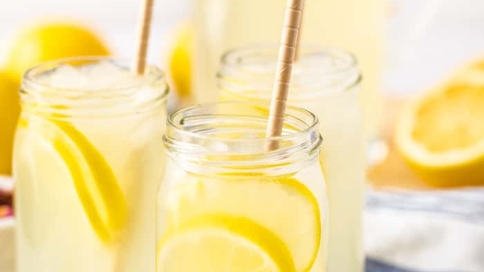 Closeup of three mason jars full of rose lemonade and lemon slices.