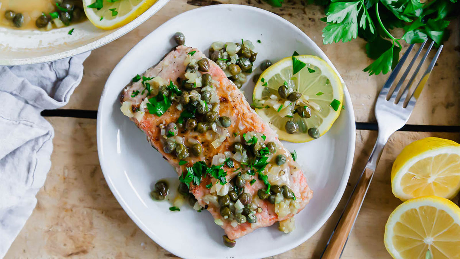 Colorful salmon piccata on a white plate.