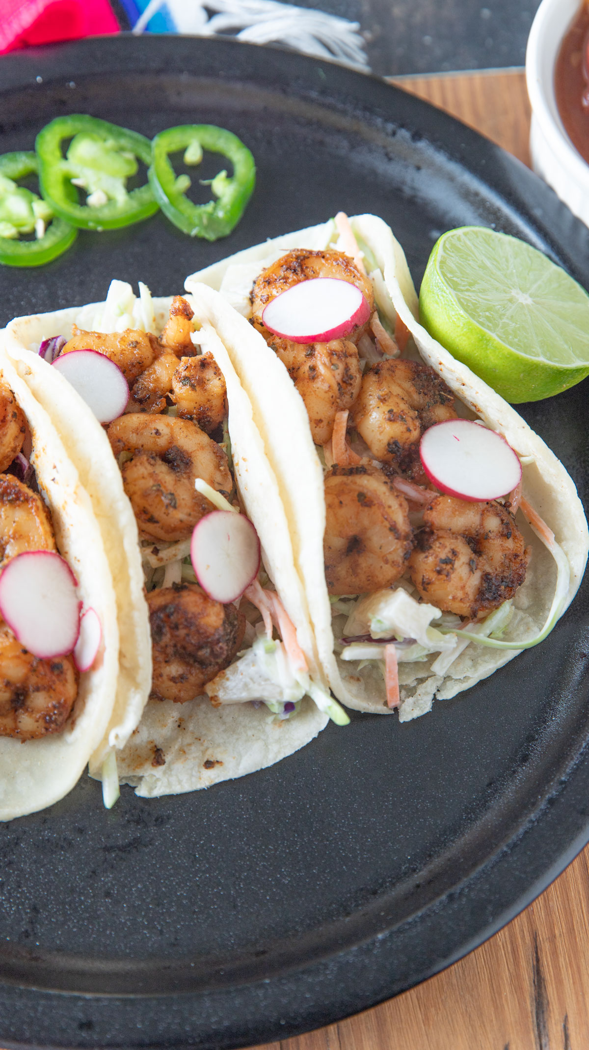 Shrimp street tacos on a black plate.
