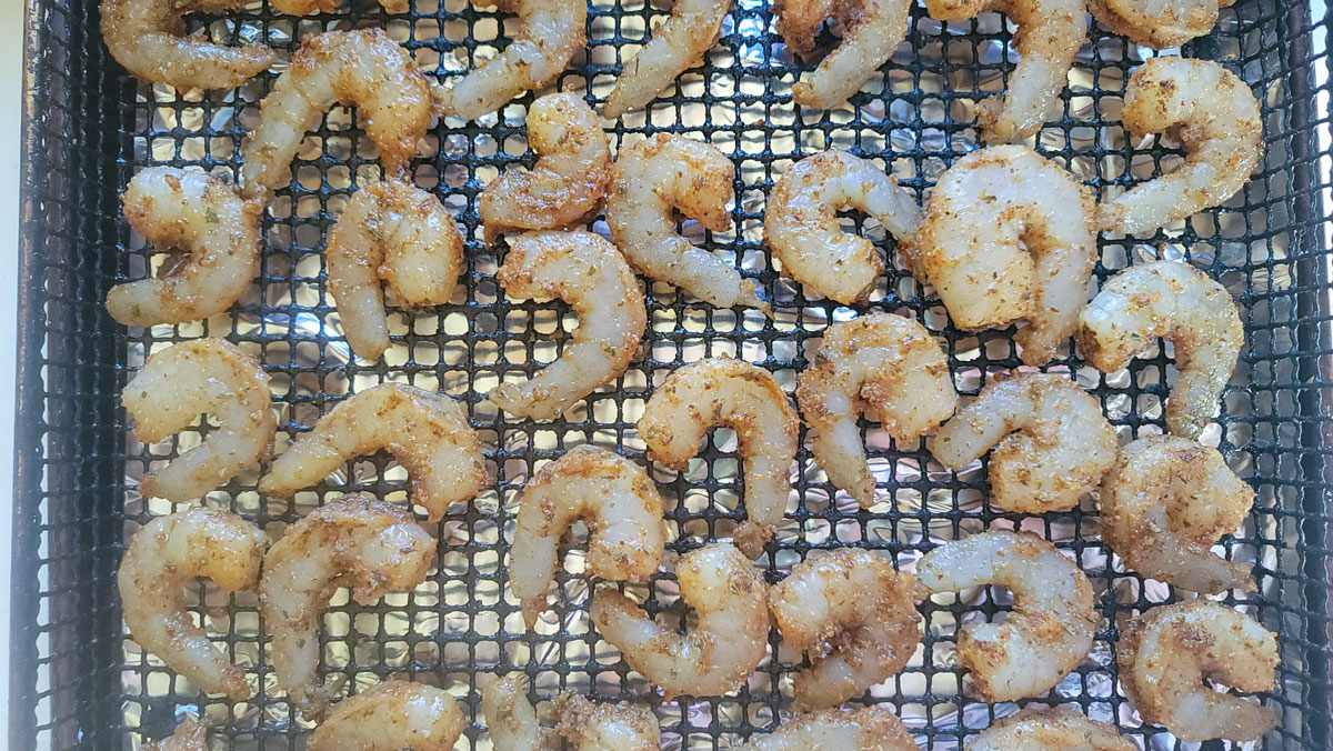 Shrimp arranged on air fryer basket.