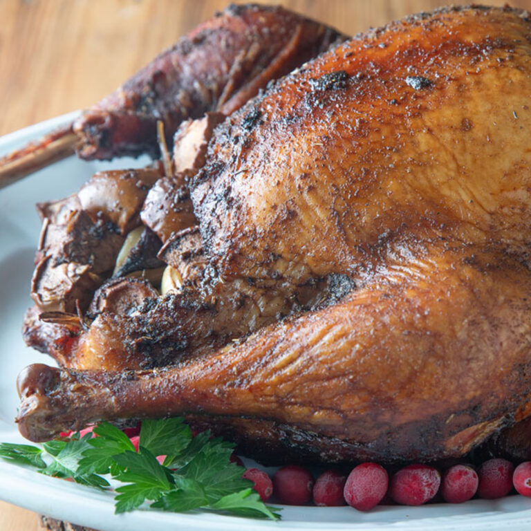 Smoked whole turkey on a white platter.
