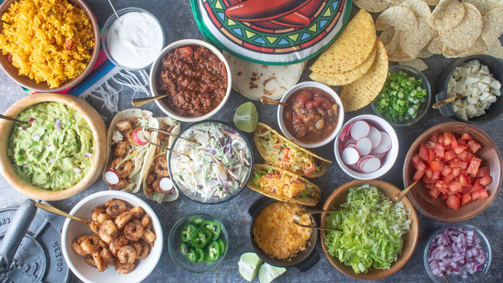 Section of a taco bar with various ramekins holding toppings and fillings.