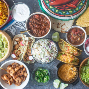 Section of a taco bar with various ramekins holding toppings and fillings.
