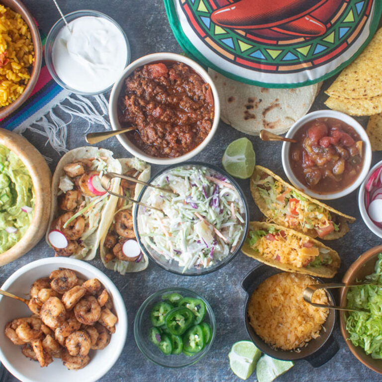 Section of a taco bar with various ramekins holding toppings and fillings.