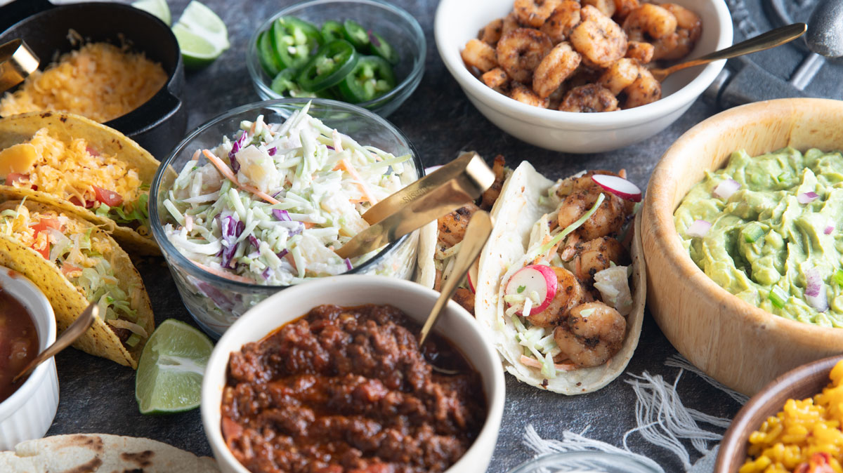 Taco fillings and toppings on a black board.