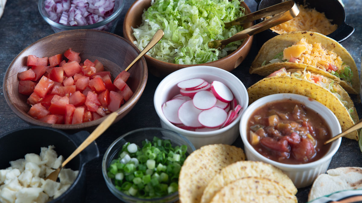 Small bowls filling with colorful taco toppings.