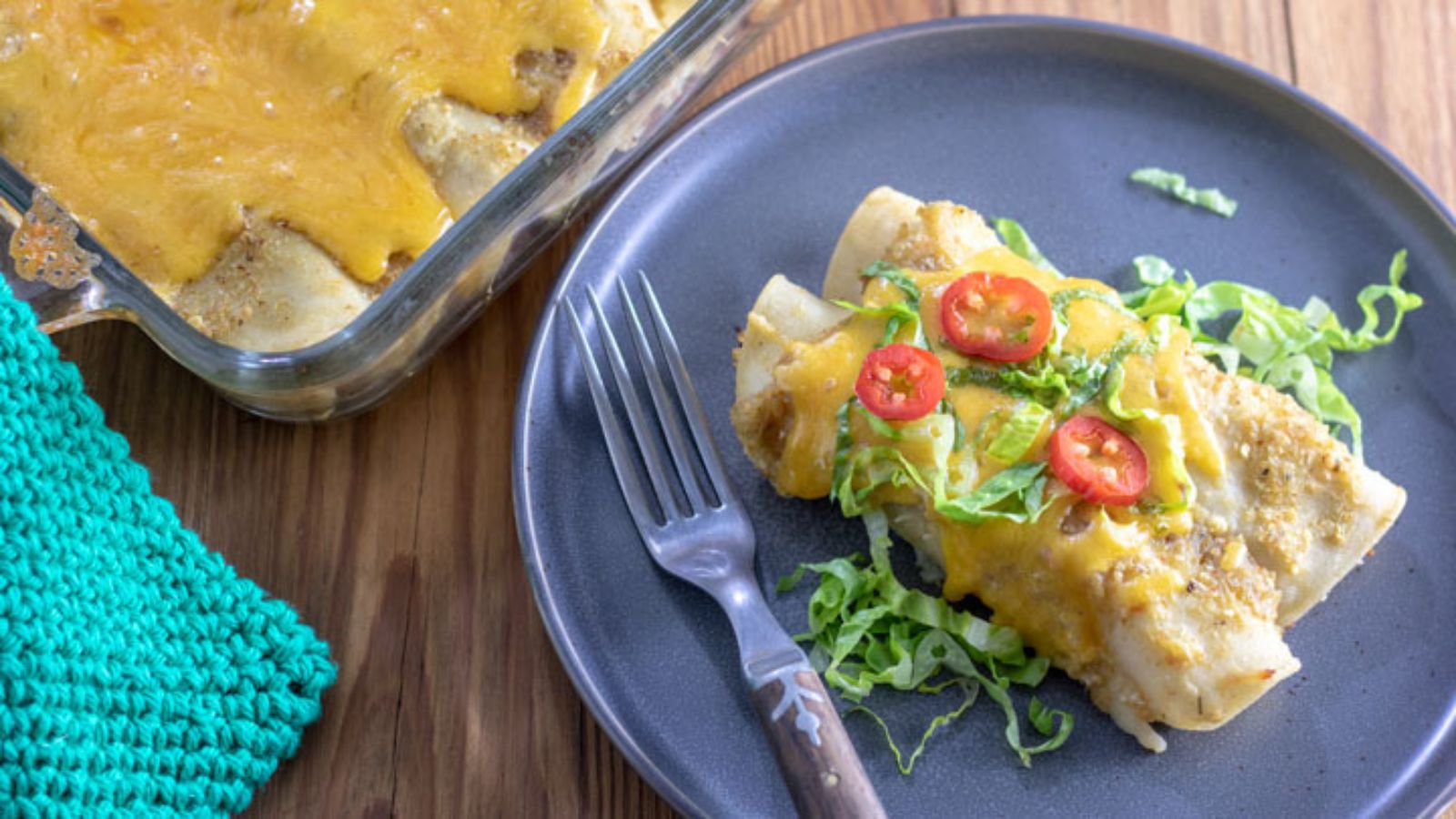 Two Turkey enchiladas served on a grey blue plate.