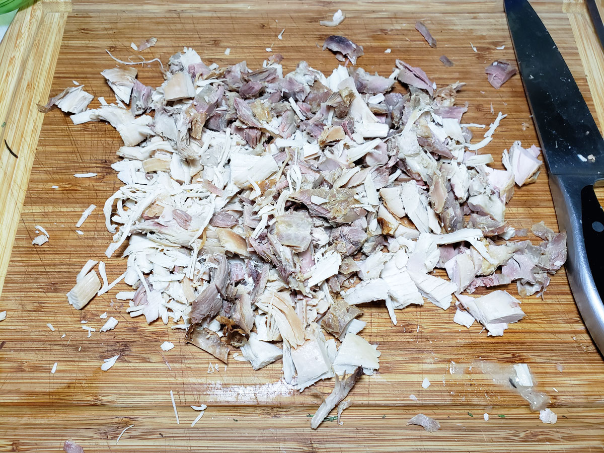 Turkey chopped up on a wooden cutting board.