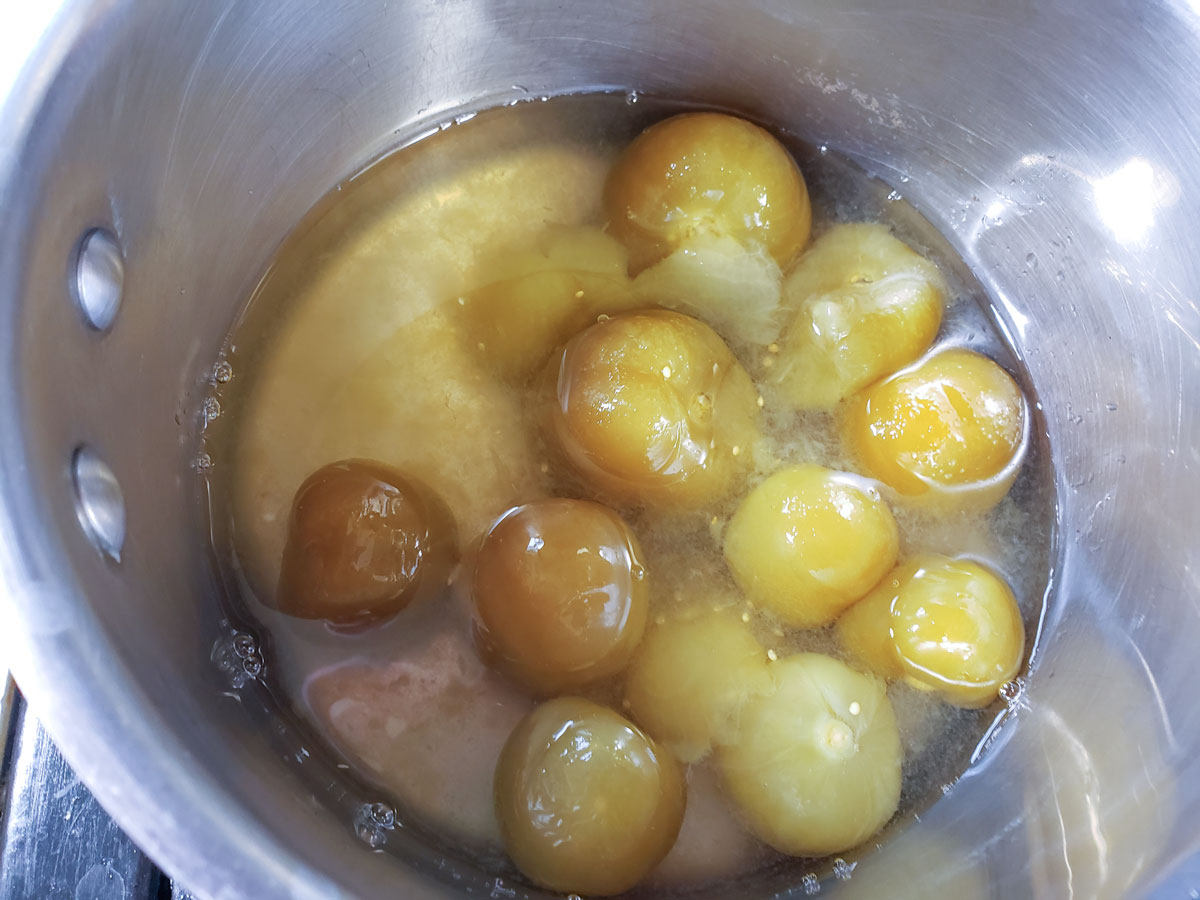 Tomatillos in a pot with water.