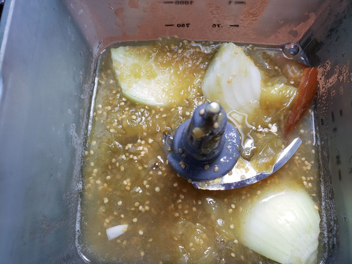 Tomatillos and onion in a blender container.