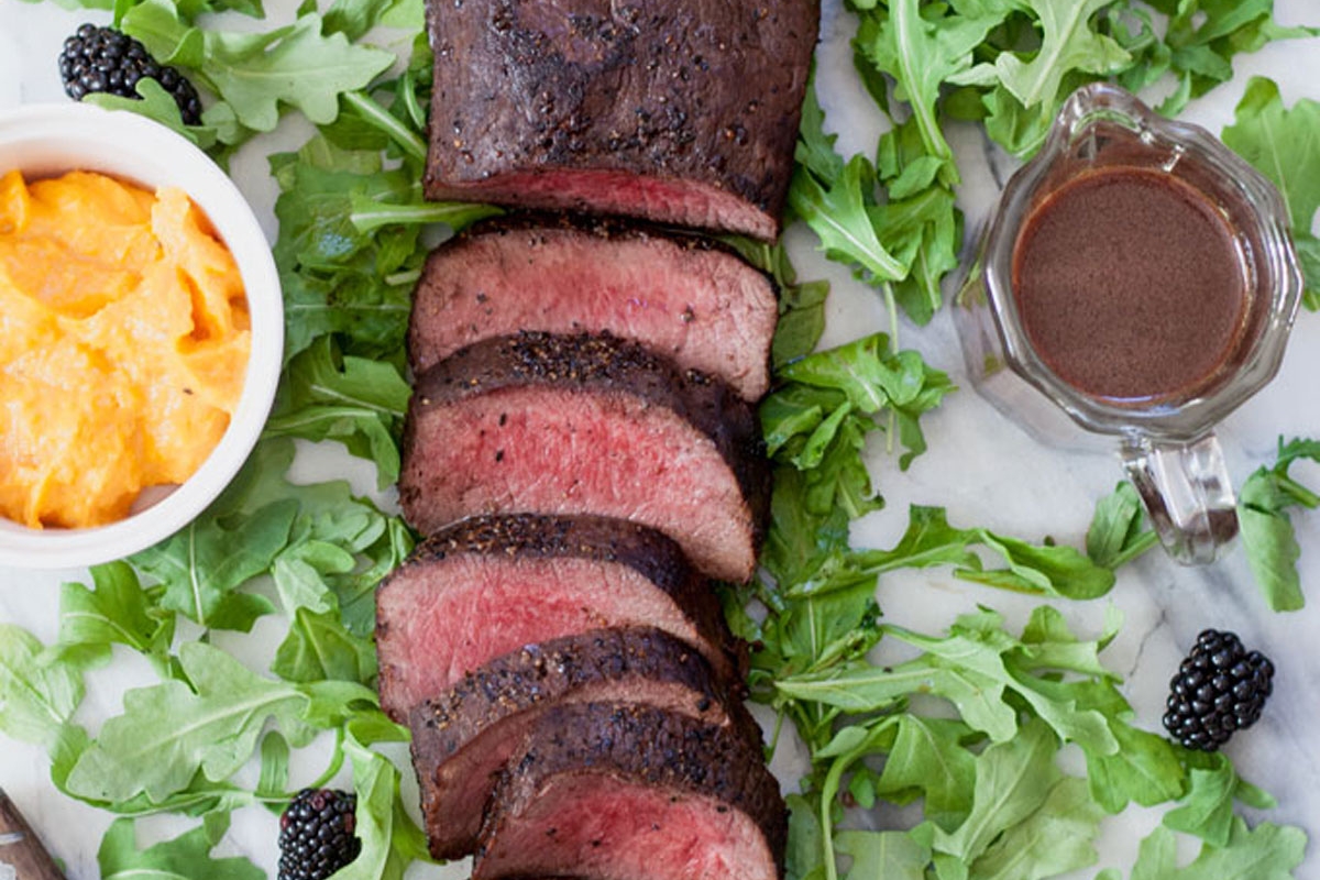 Close up of sliced venison loin on a bed of argula.