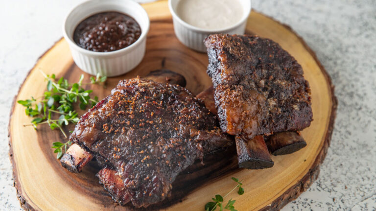 Two racks of smoked ribs on a wood round.