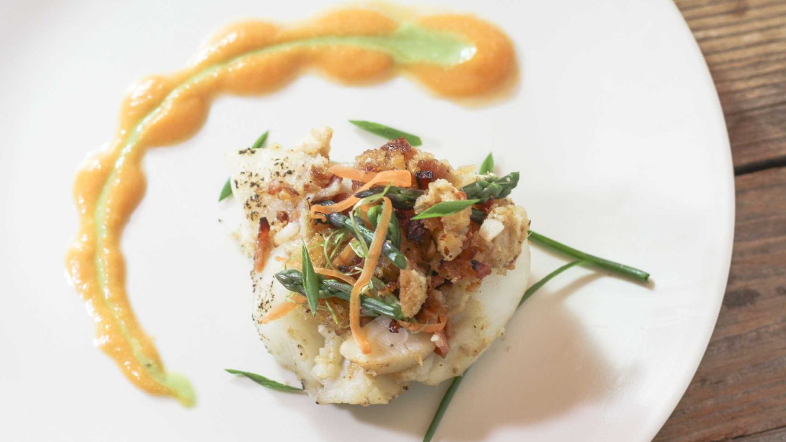 Bacon Horseradish Lobster Stuffed Grouper on a white plate garnished with asparagus and carrot shavings.