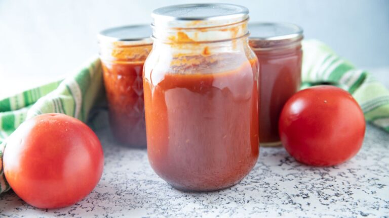 Pint jar with tomato ketchup with fresh tomatoes and a green towel.