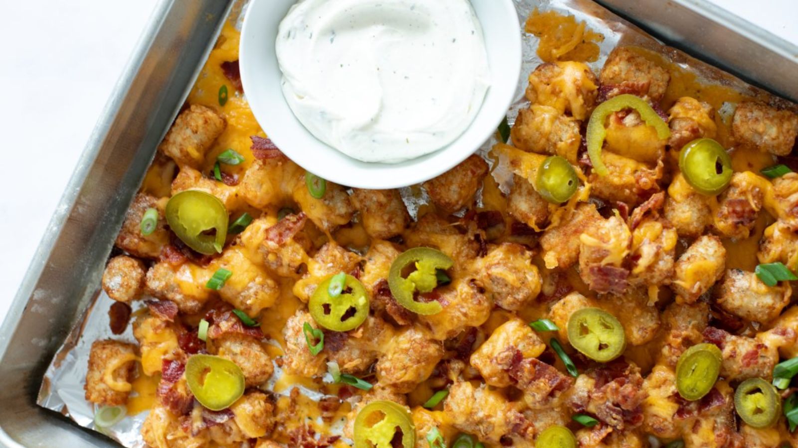 Cheesy tater tots in a baking dish with ranch dip