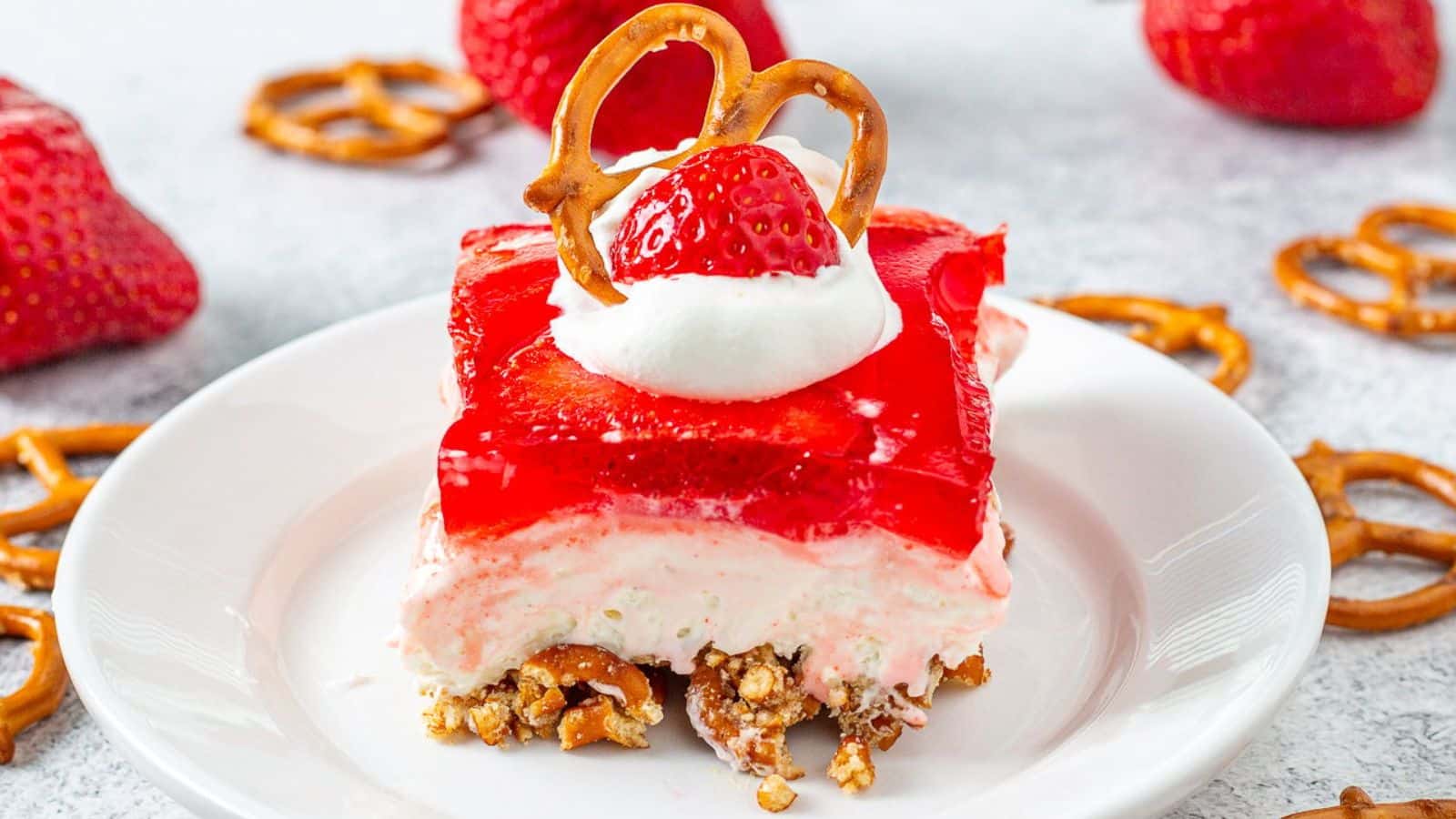 A slice of strawberry pretzel cake on a white plate.
