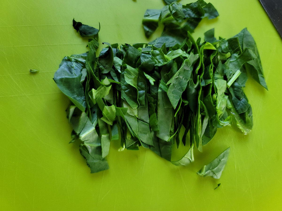 Chopped spinach on a green board.