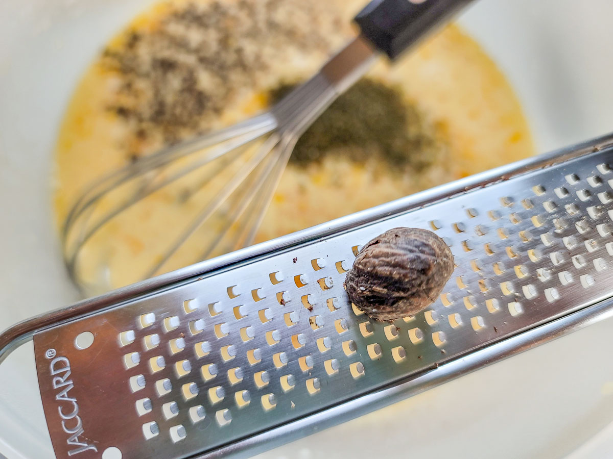 Grating whole nutmeg into egg mixture.