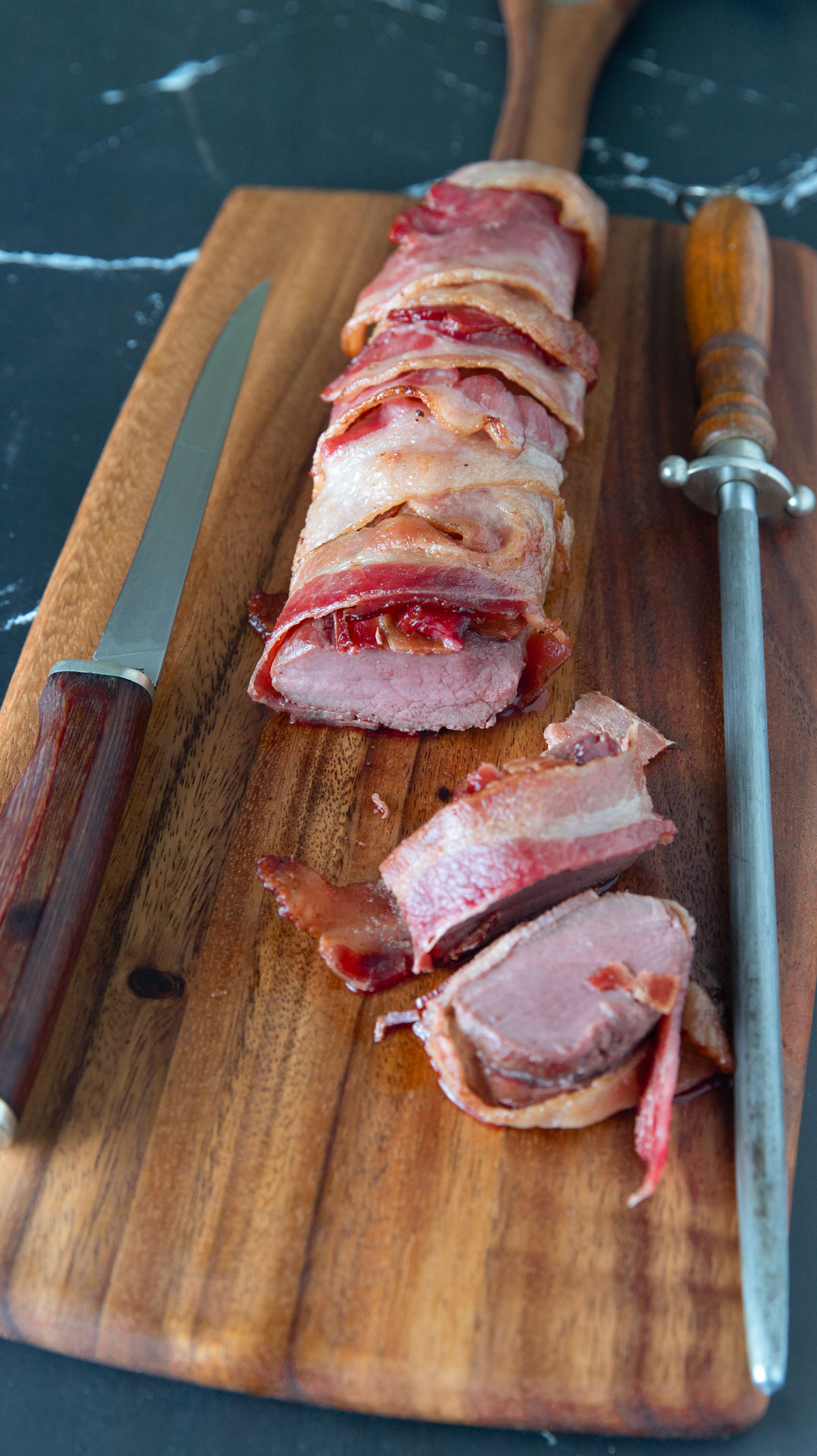 Sliced venison backstrap wrapped in bacon.