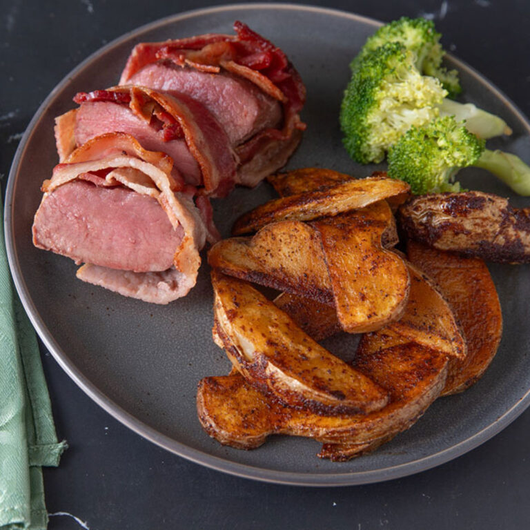 Medium rare sliced venison loin with roasted potatoes.