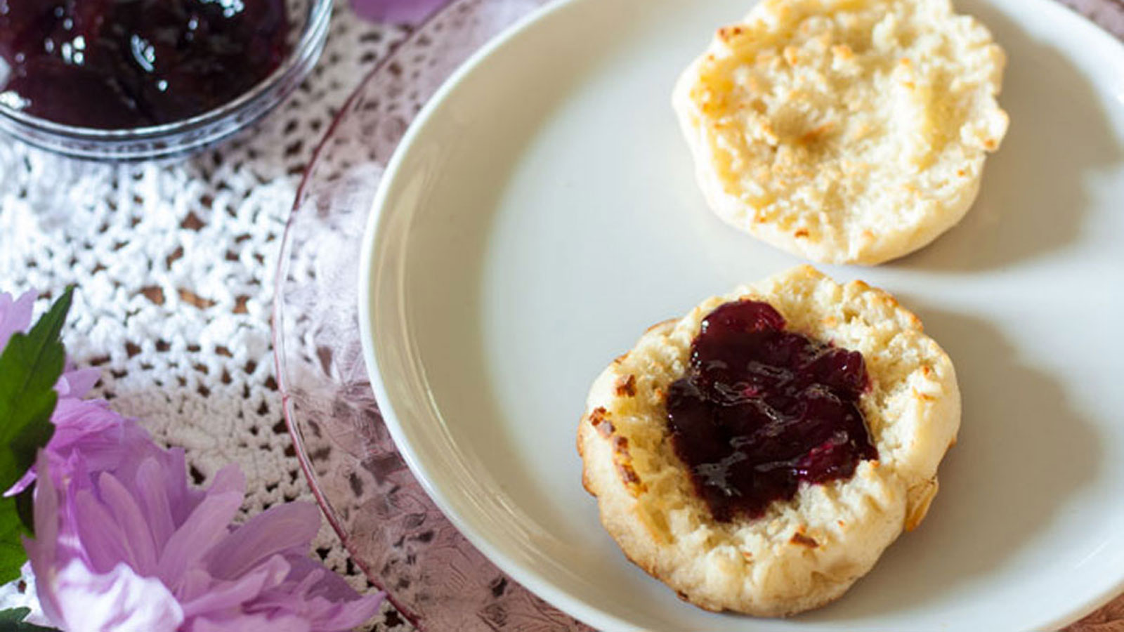 Blackberry jam on muffin with jars of jam.
