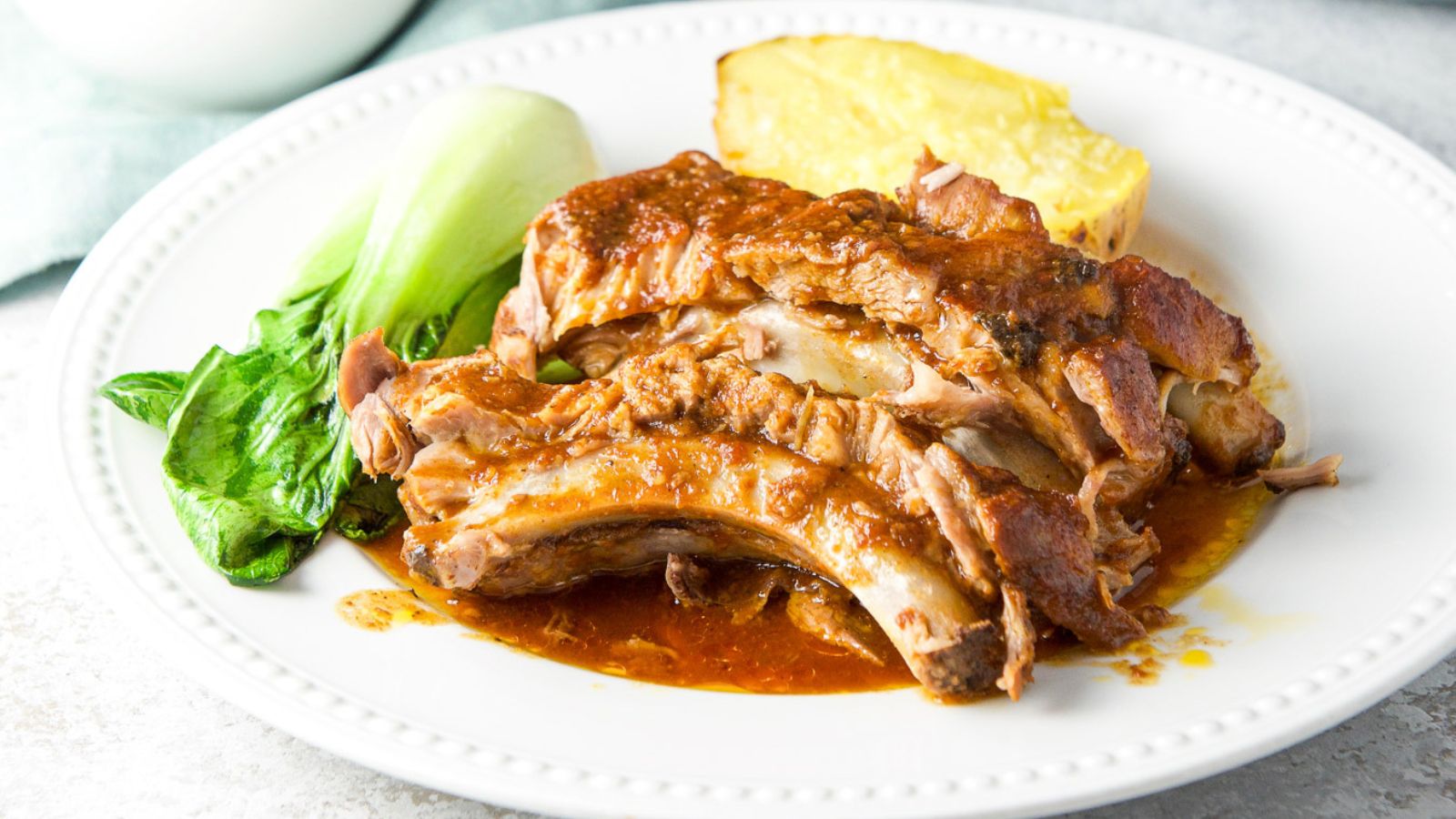 Baby back ribs on a white plate.