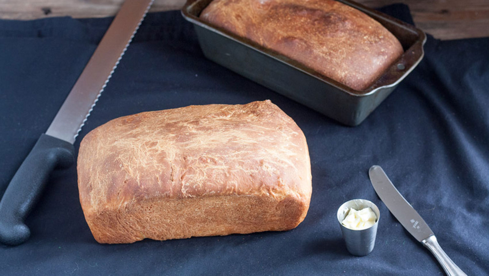 Two whole loaves of brioche on a black tablecloth.