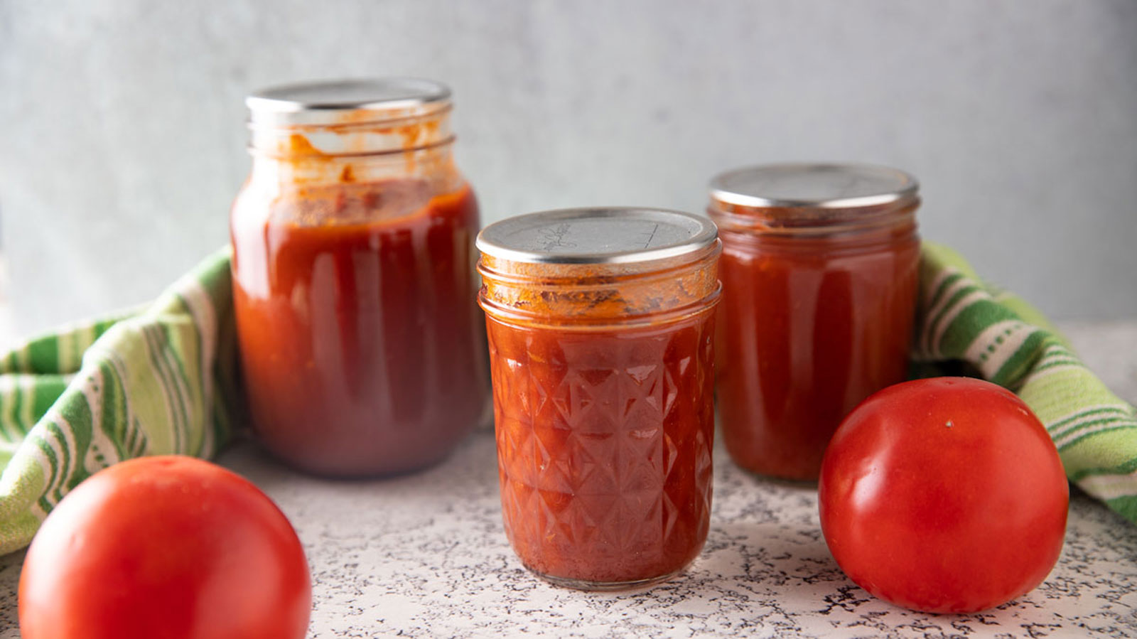 Jars of ketchup with fresh tomatoes.
