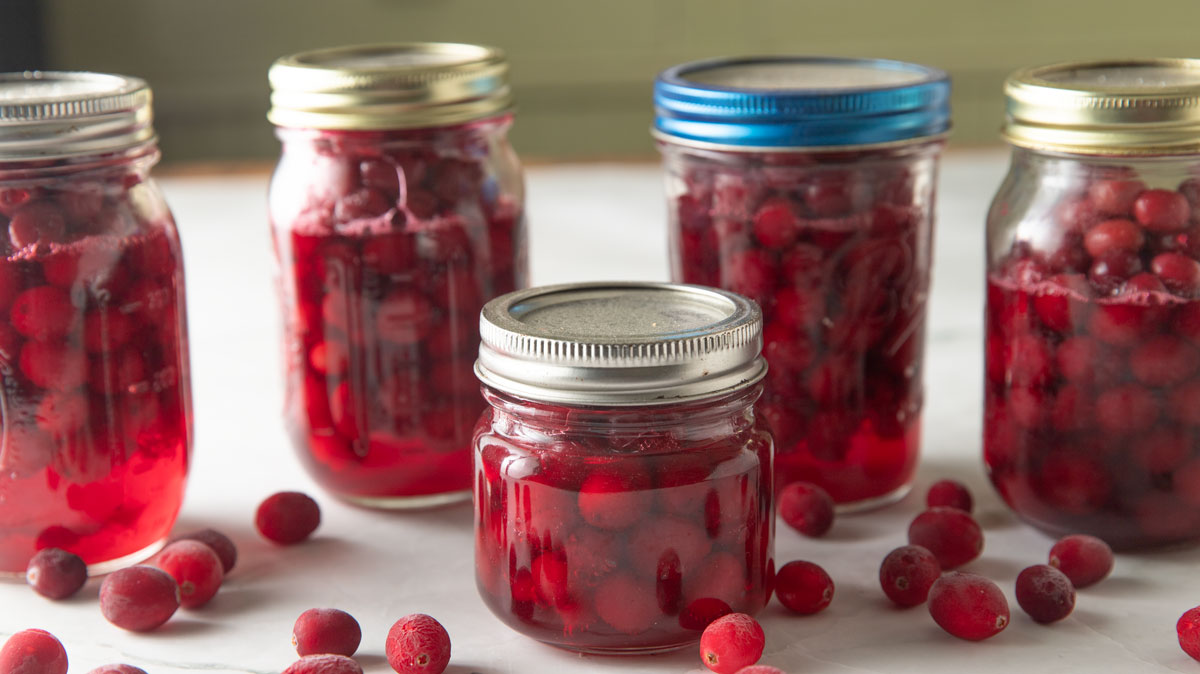 Jars of canned cranberries on a white board.