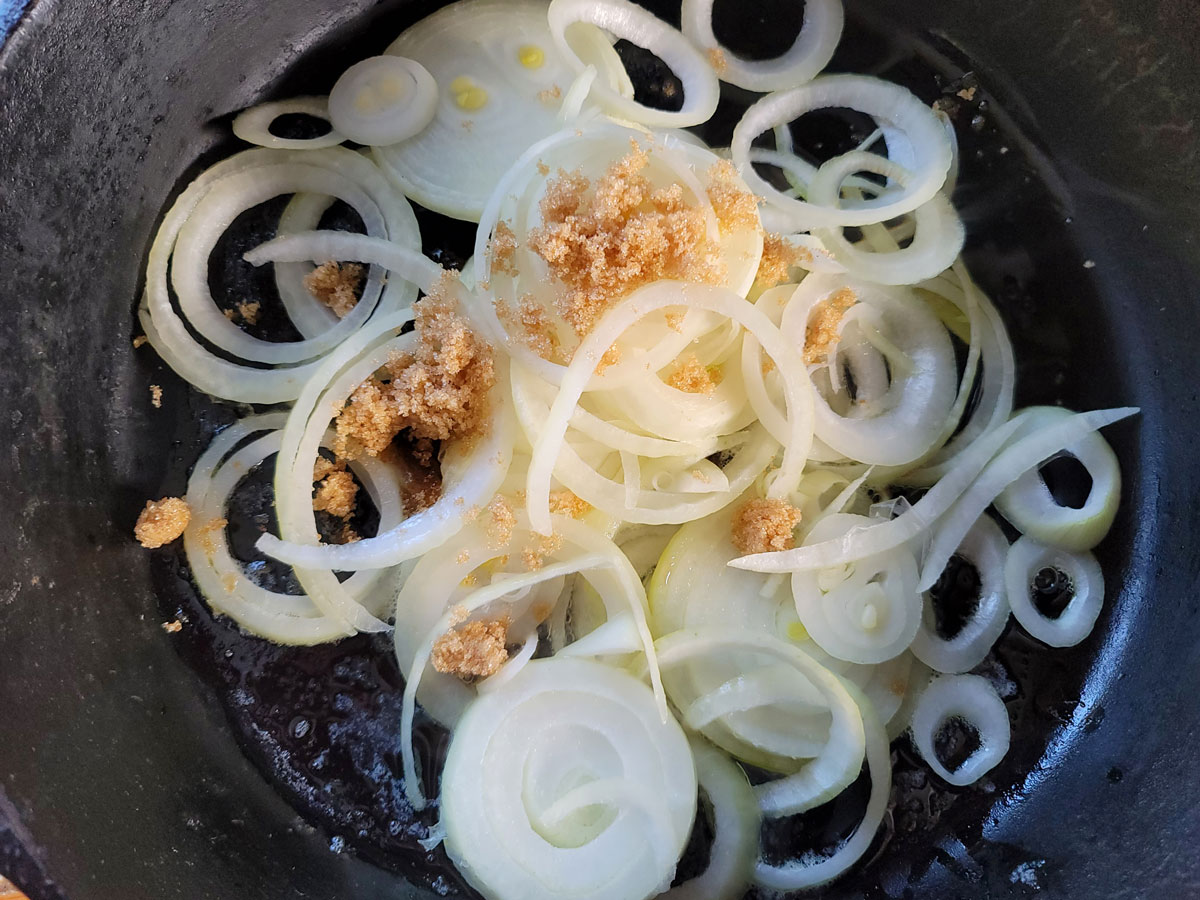 Onions sprinkled with brown sugar in skillet.