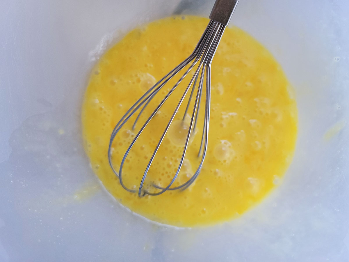 Eggs whisked in a plastic bowl.