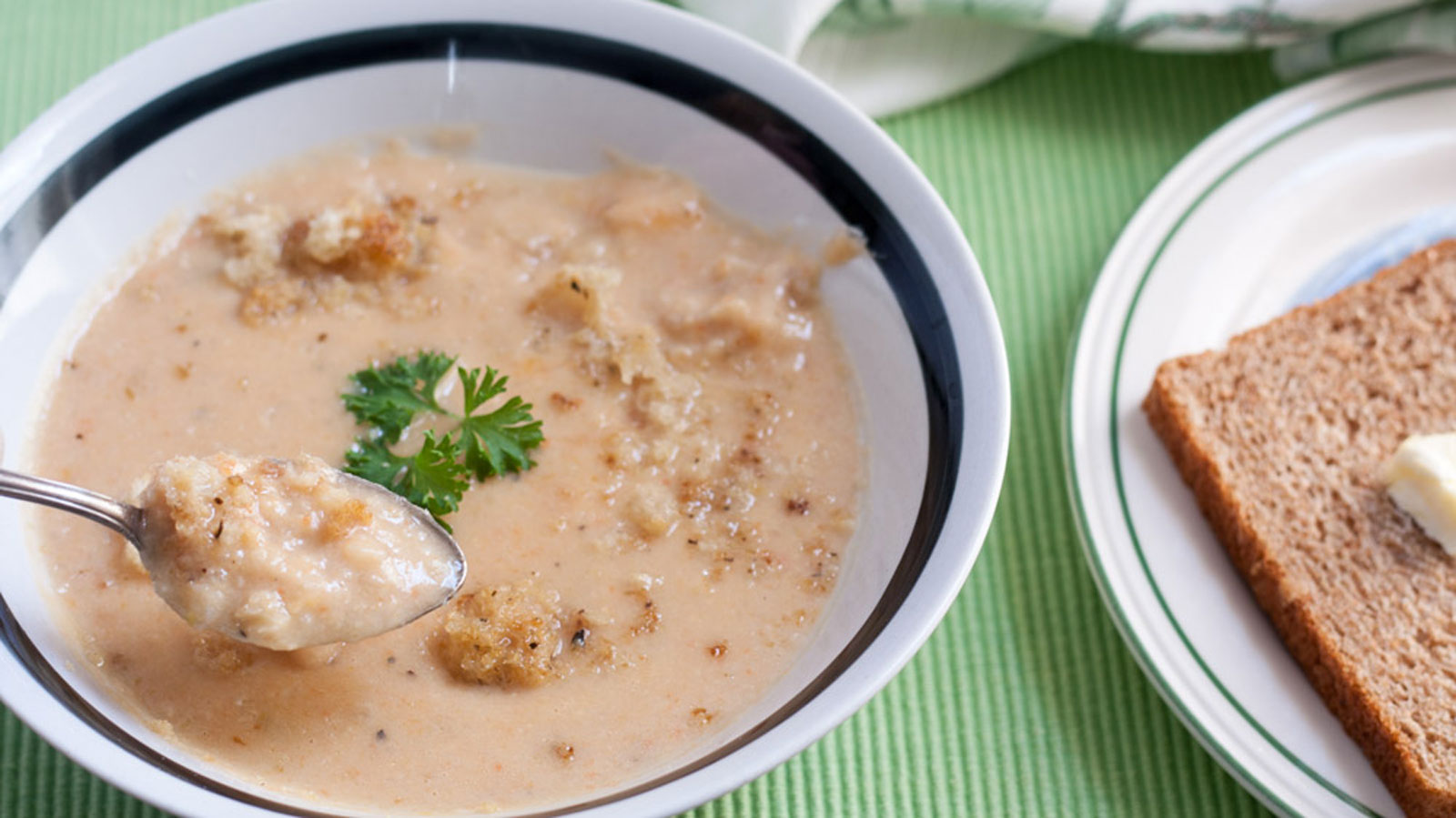Cheesy cauliflower soup in white bowl with black trim.