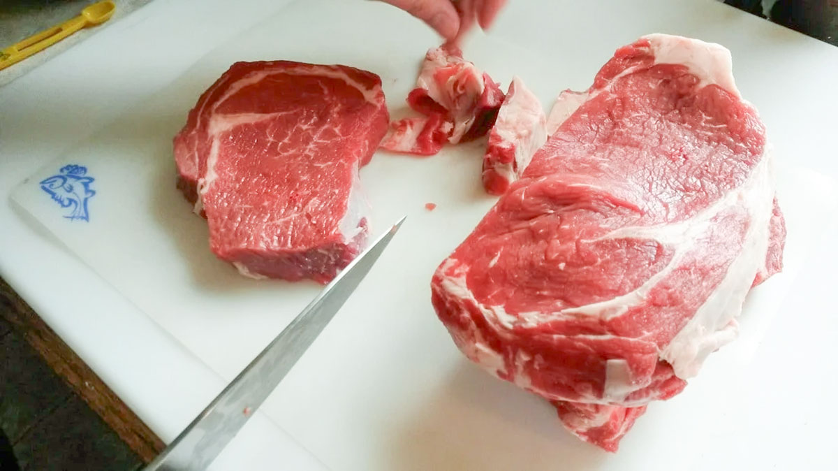 Trimming large fat areas from steaks.