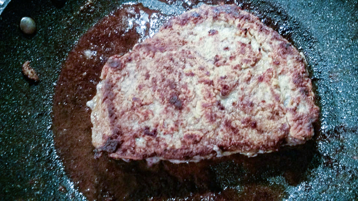 Flipped meat with one side browned.
