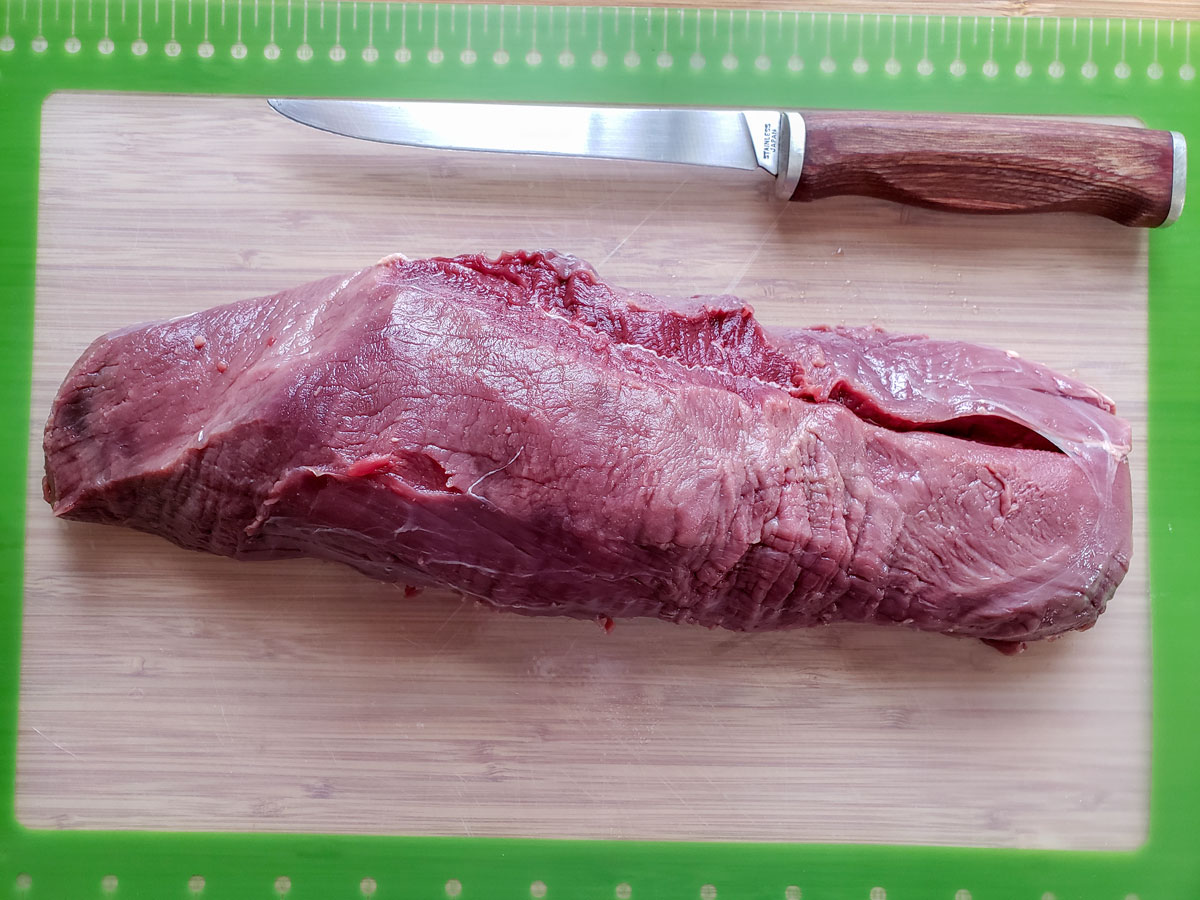 Trimmed venison loin on a cutting board.