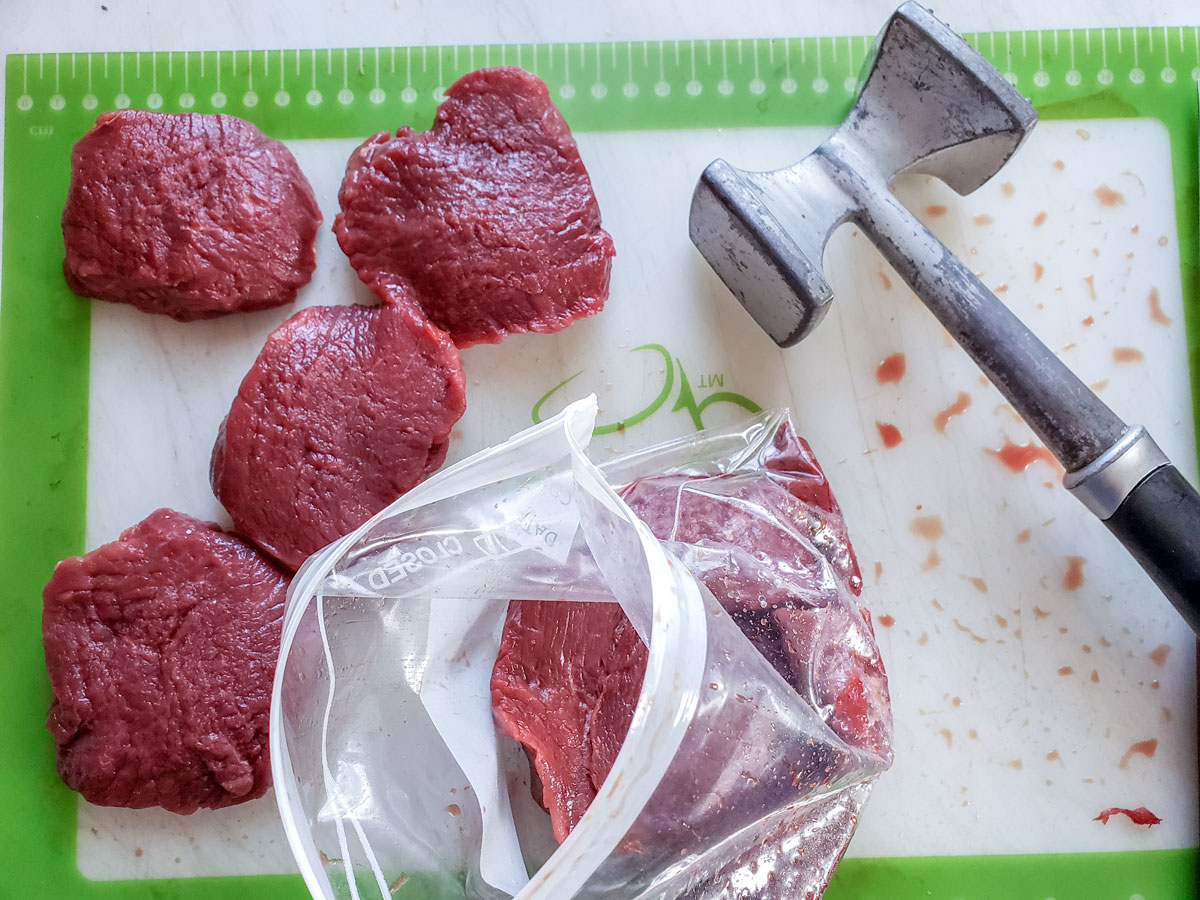 Pounding out a steak in a plastic bag.