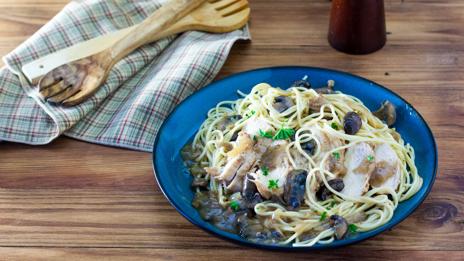 Sliced chicken and mushrooms on a bed of spaghetti.