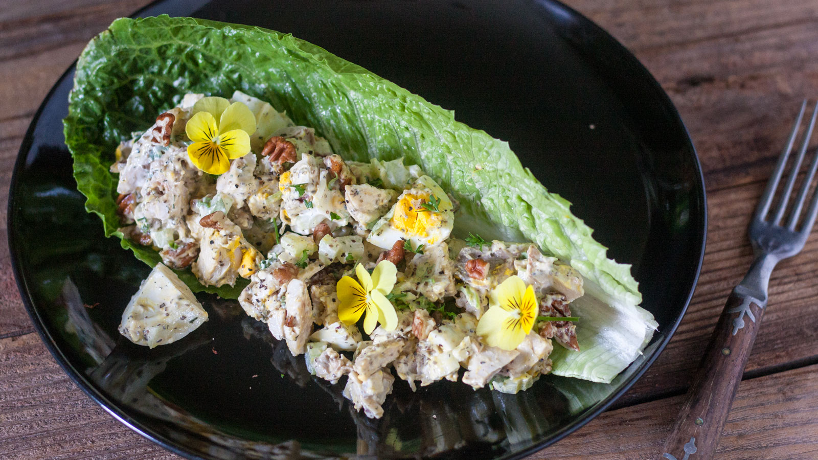 Chicken salad served on a Romaine Lettuce leaf with edible flowers.