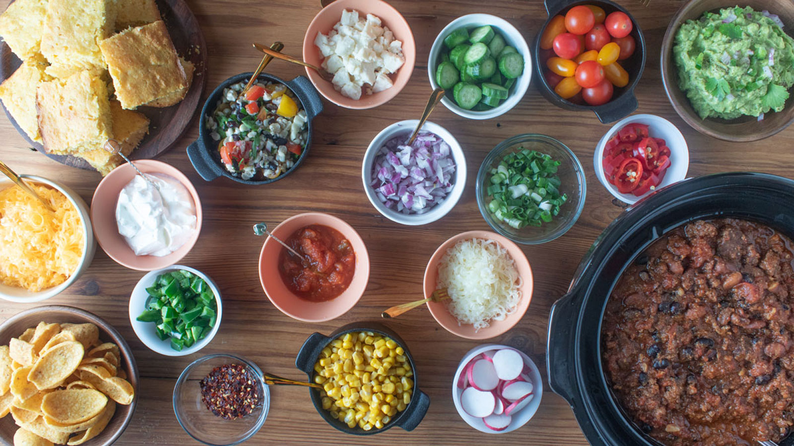 Crockpot with chili and small bowls with various toppings.