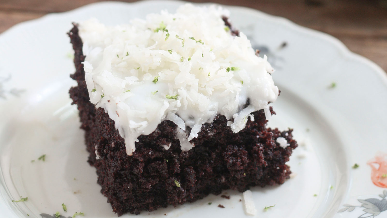 Slice of chocolate cake topped with frosting and shredded coconut.