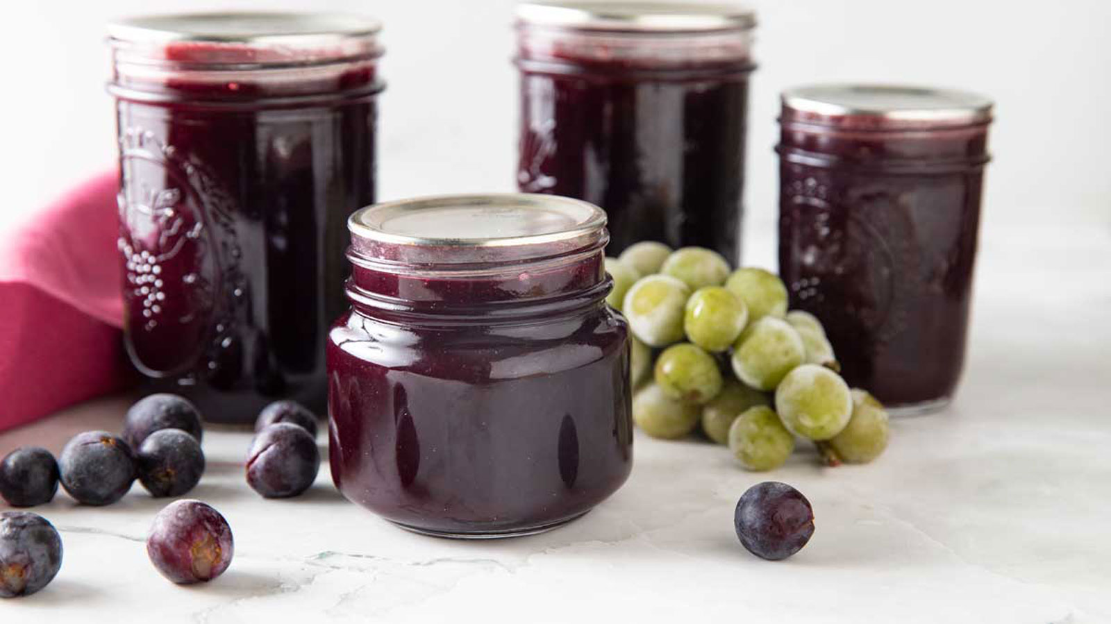 Jars of grape jelly with fresh grapes