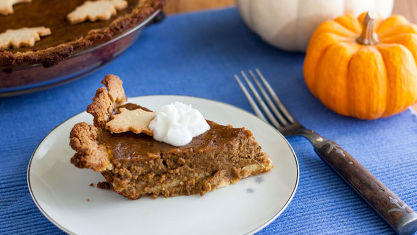 Dairy free pumpkin pie slice with dollop whipped cream on white plate