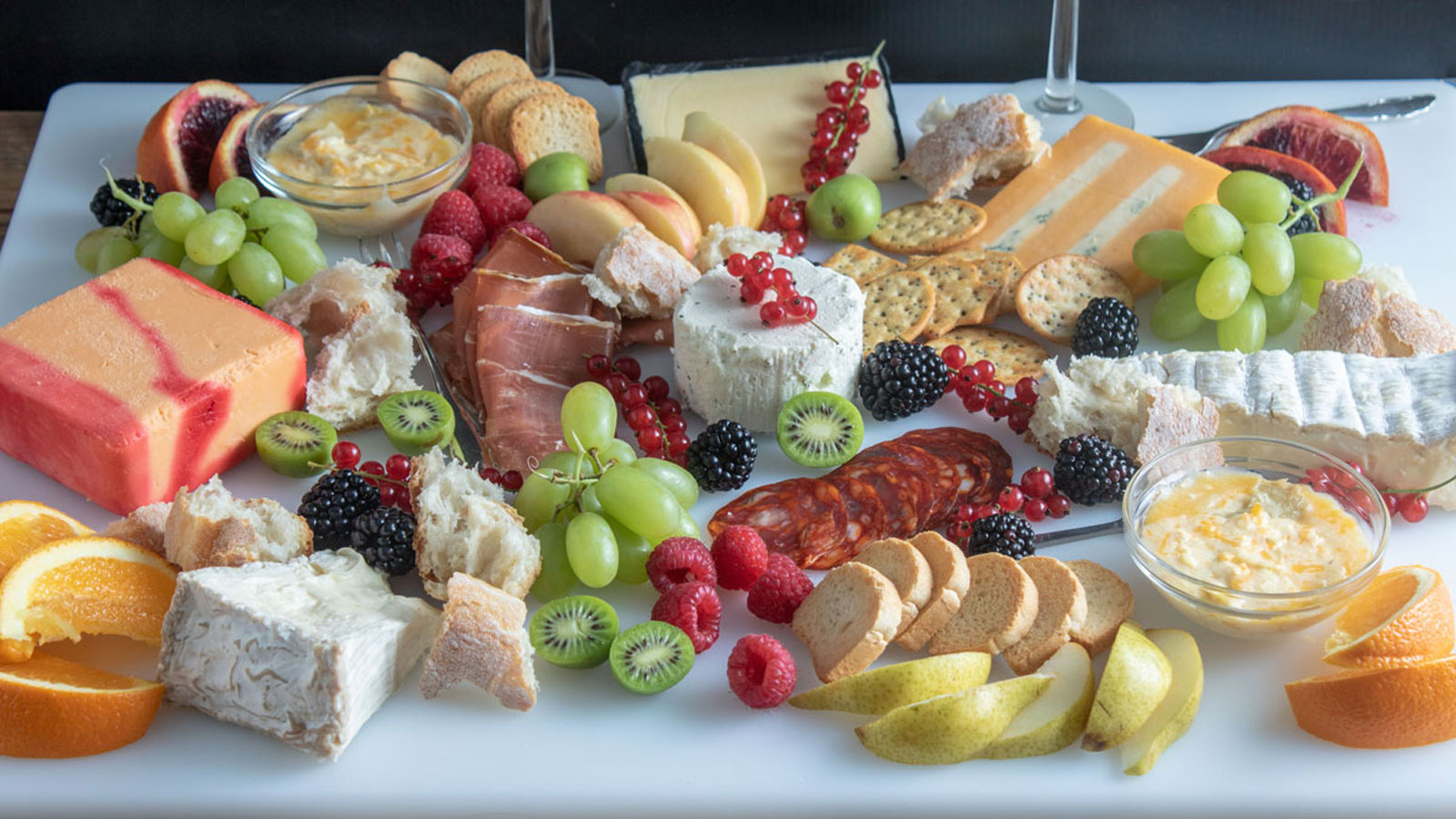 Large platter filled with various cheeses, fruit, bread and crackers.