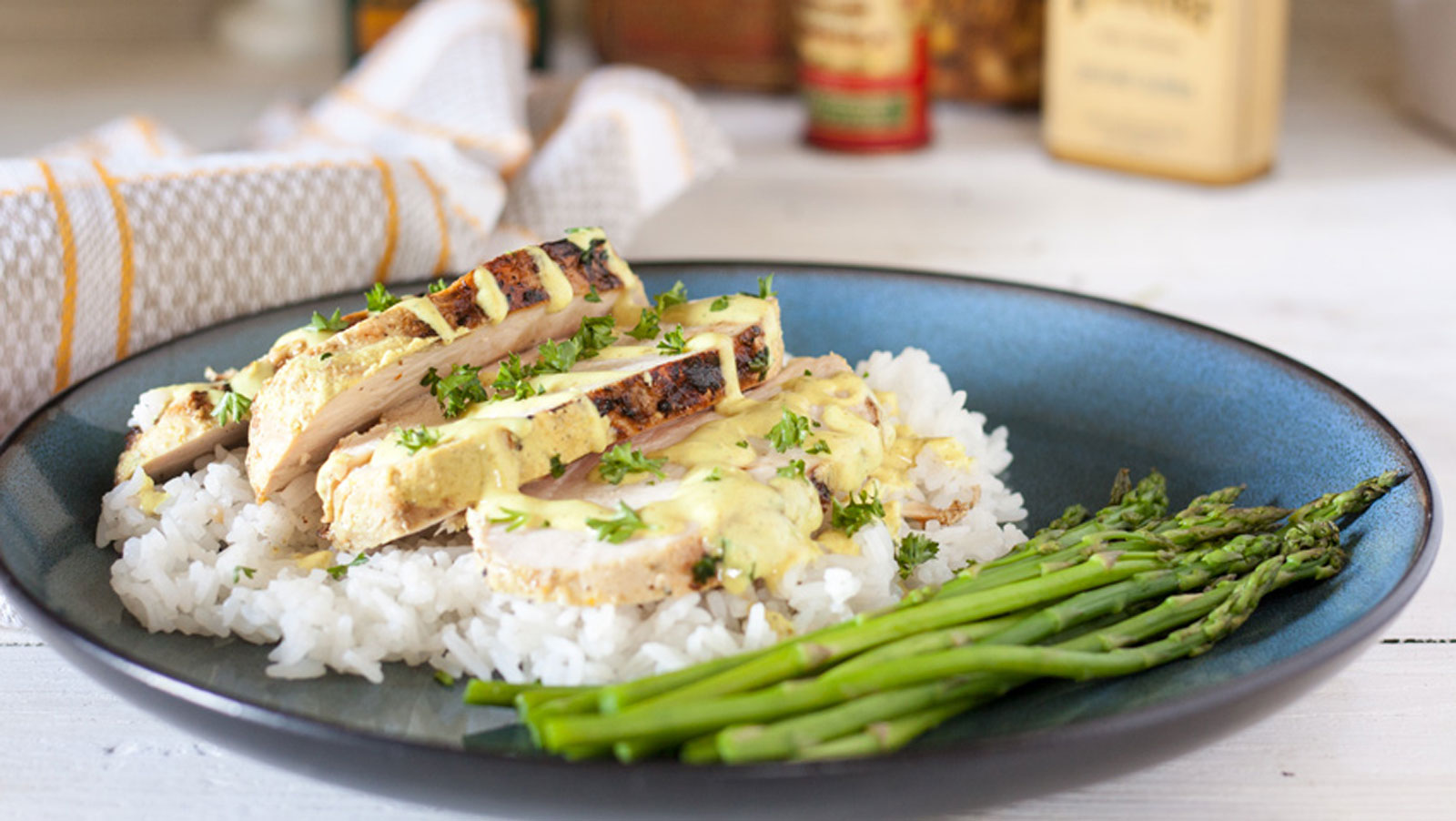 Sliced chicken breast on top of a bed of rice with coconut curry drizzled on top.