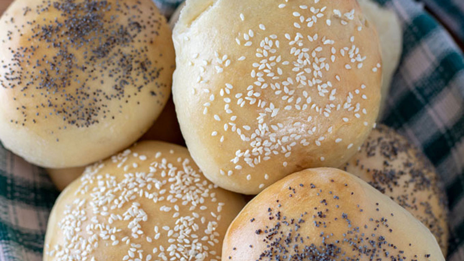 Close up sesame seed bun in a basket with other buns.