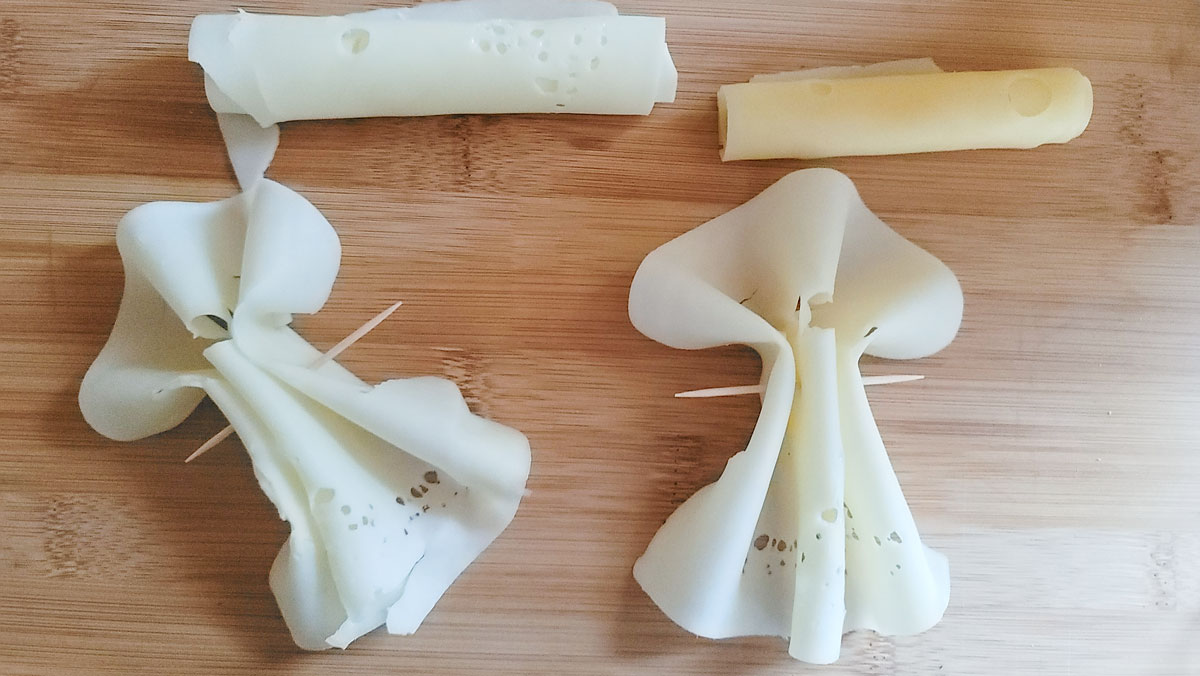 Four pieces of cheese. Two rolled into logs and two accordioned.