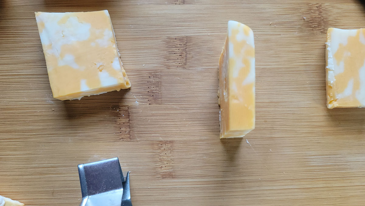 Half inch slice of cheese on a cutting board.