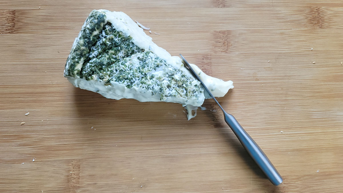Soft cheese knife cutting off a piece of soft brie.