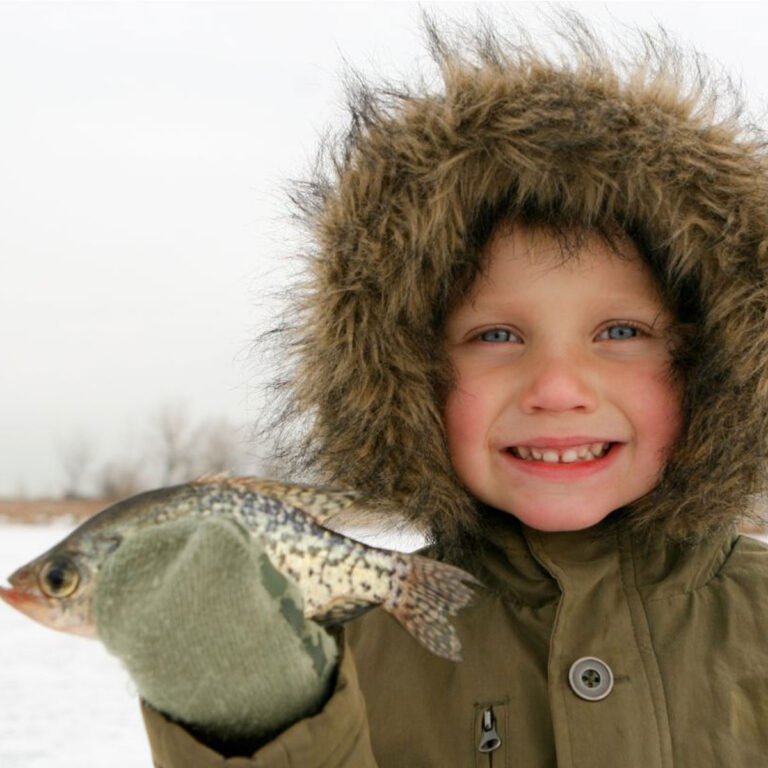 Small child holding a freshly caught fish.